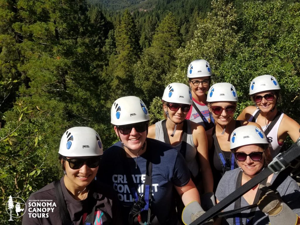 Part of the ziplining group smiles for a photo in the canopy of the redwood forest!