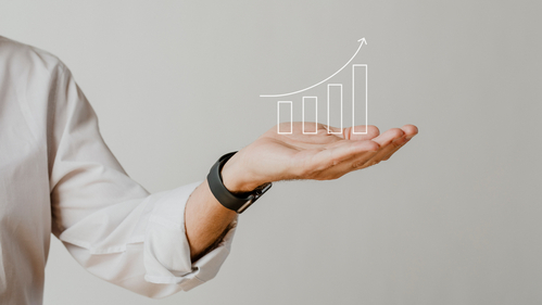 A bar graph with increasing bar height superimposed over a man's outstretched hand.