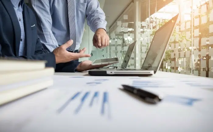 People in front of a laptop discussing about financial charts.